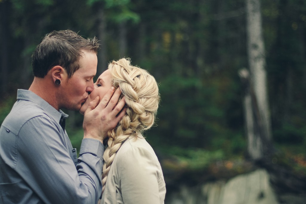 newly engaged white couple from golden bc kisses as he holds her face in his hands