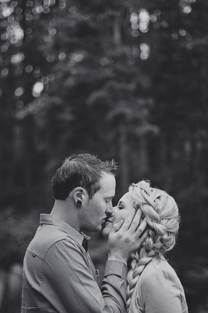 man holds his fiance's face in his hands and gently kisses her lips