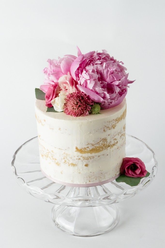 a tall naked cake on a pedestal with flowers on top in this naked cakes branding photography session in golden bc 