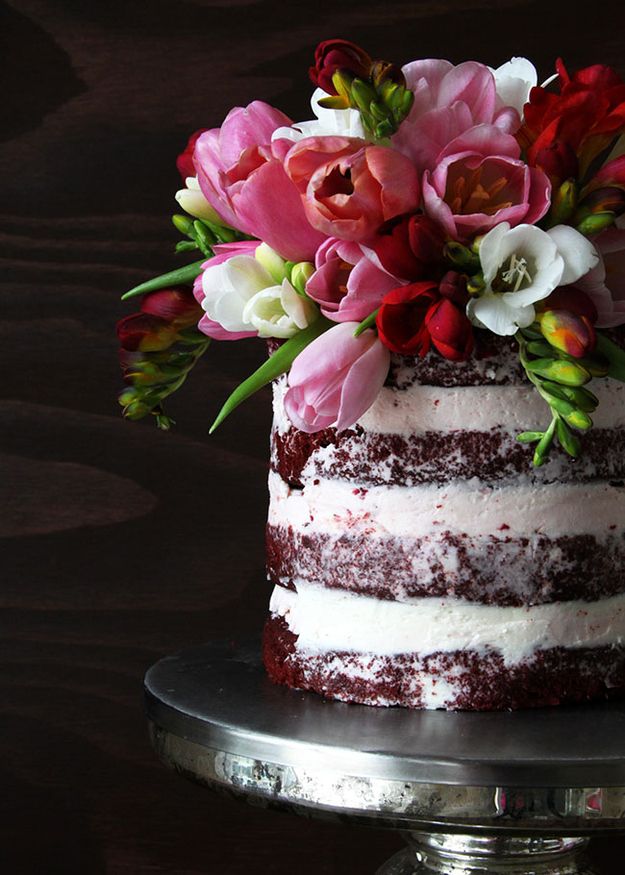 red velvet cake with no icing on the outside, only in between layers, and with a bouquet of flowers on top