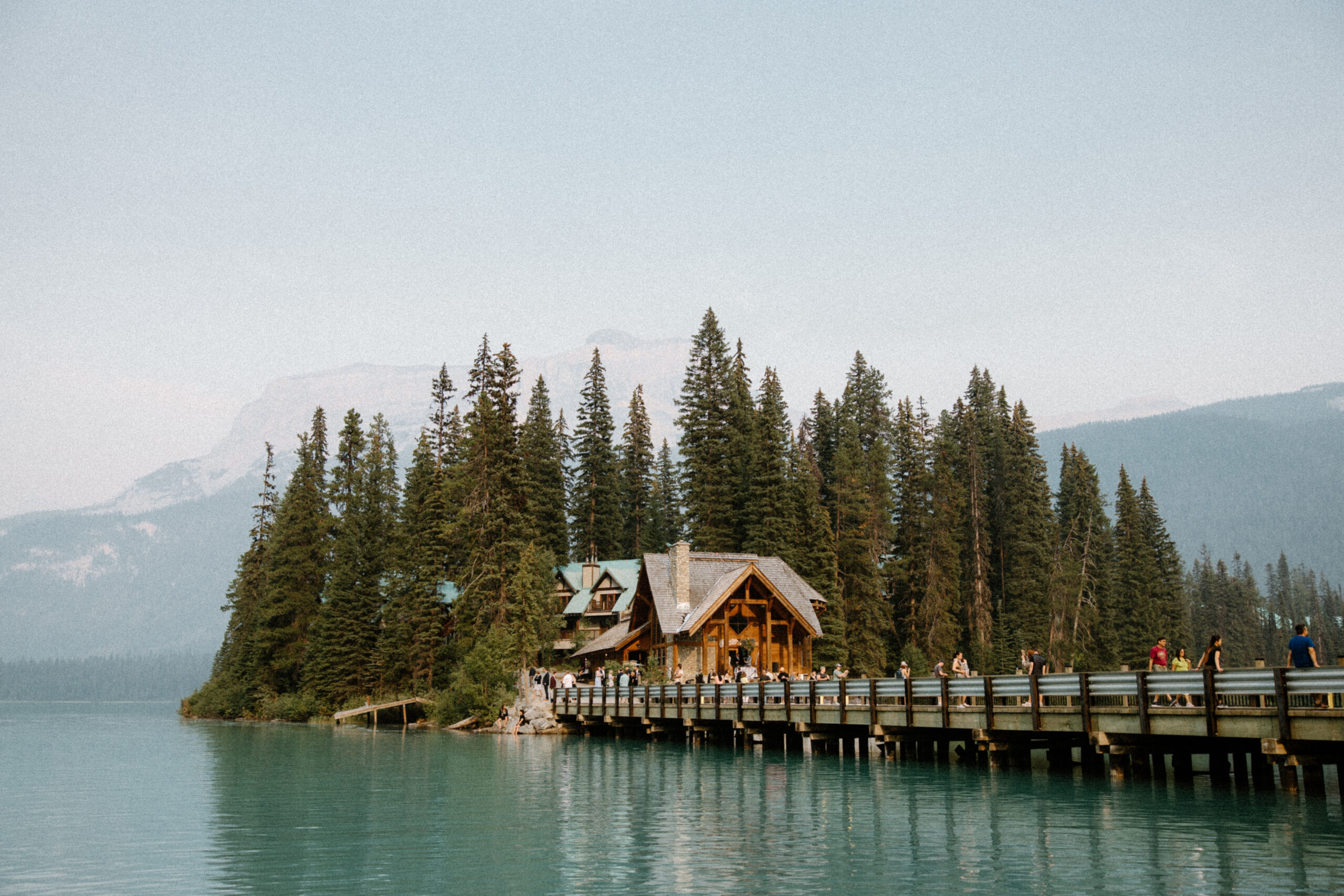 scenic mountain landscape of walkway above water leading to Emerald Lake Lodge surrounded by trees